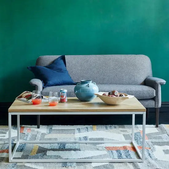 A rectangular Mangifera Ika Carbon Coffee Table with a mango wood top and white painted metal base.