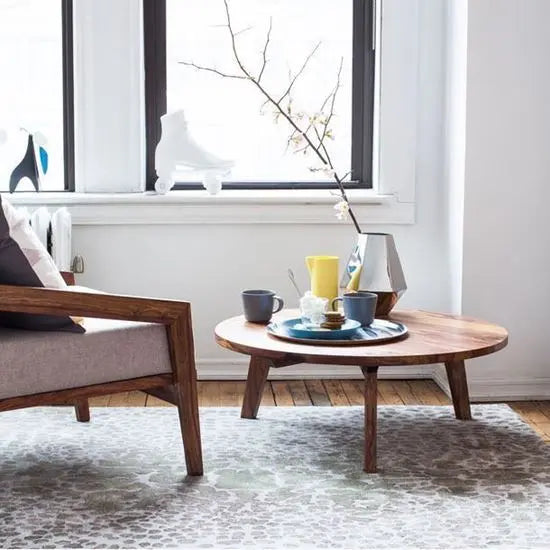 A low-height, round coffee table made of sheesham wood with knockdown legs.