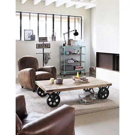 A rectangular coffee table with a distressed mango wood top and metal movable wheels.