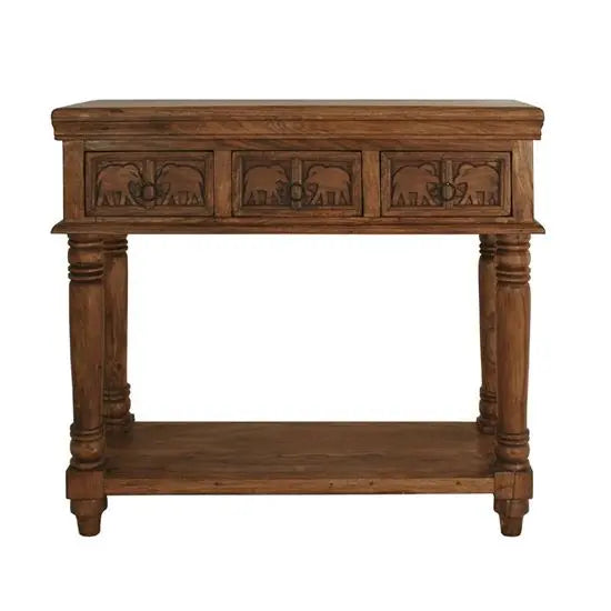 A wooden console table with three drawers and carved details, finished in a warm brown hue. With shelve at bottom.
