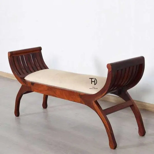 An Amira lotus bench with arms on each side, made of solid Sheesham wood with a honey finish and covered in off white color soft fabric.