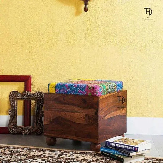 A wooden storage stool with a multicolored patchwork fabric top.