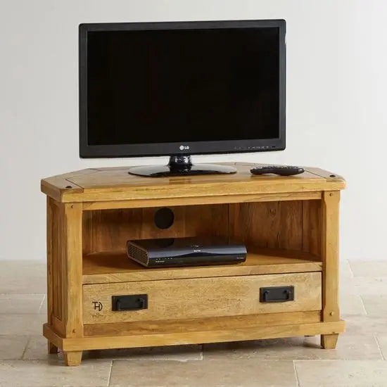 A wooden corner TV cabinet with a flat-screen TV on top and a drawer with metal handles.