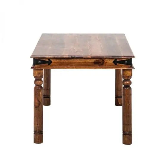 A vintage style dining table made of Sheesham wood with a rectangular top and carved legs, designed to seat five people.