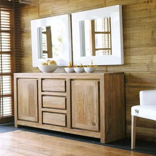 A wooden sideboard with multiple drawers and doors. The sideboard has a mirror above it, reflecting part of the room.