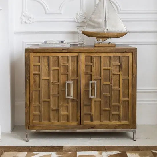 A brown wooden sideboard with two doors and metal handles, placed on a patterned rug.