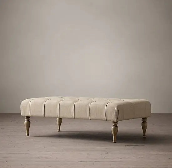 An upholstered cream fabric coffee table with tufted design.