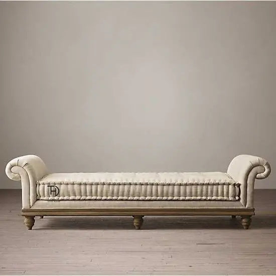 A beige upholstered lounge couch with rolled arms and a cushioned seat on a wooden frame.