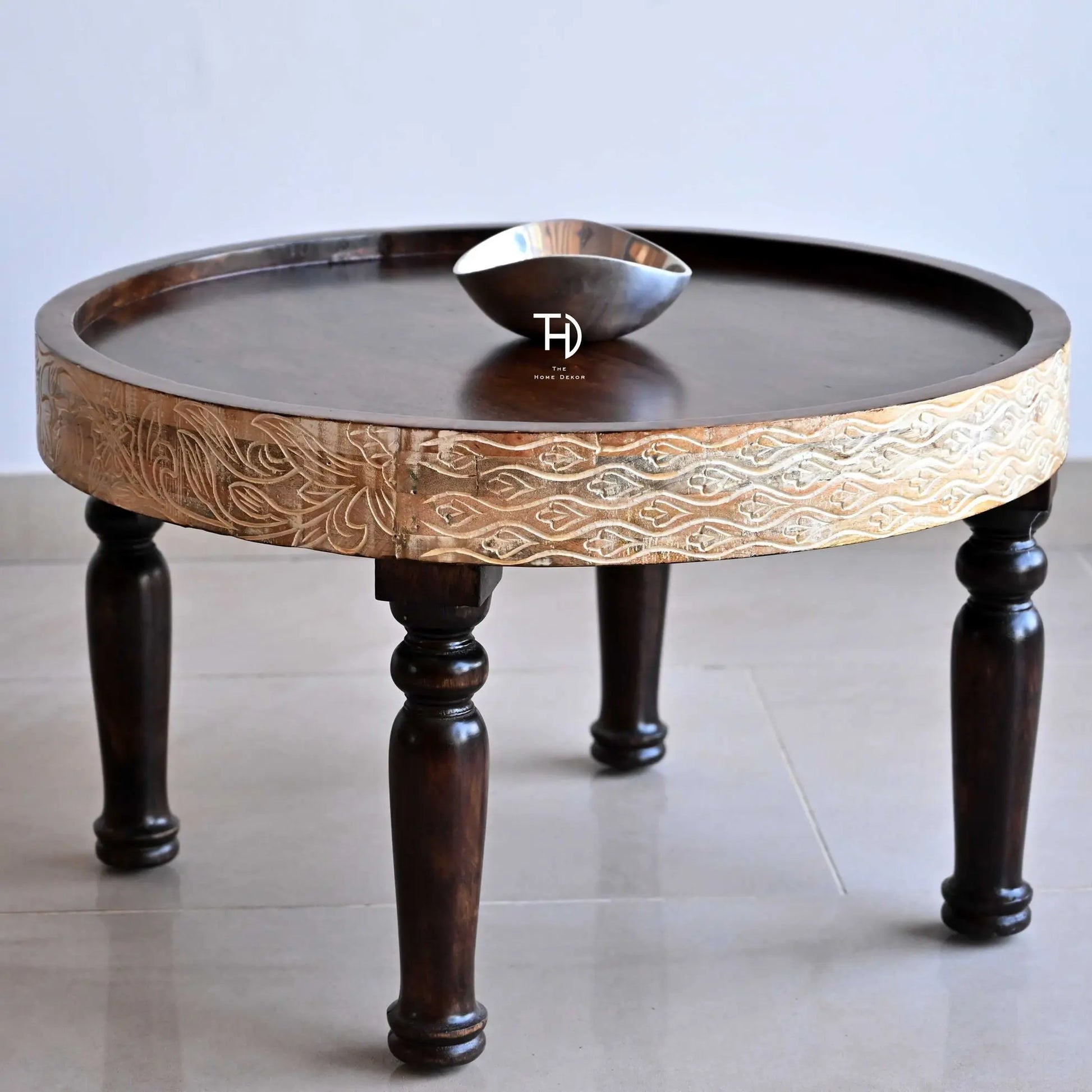 A wooden coffee table with a decorative pattern on the tabletop supported by four curved legs.