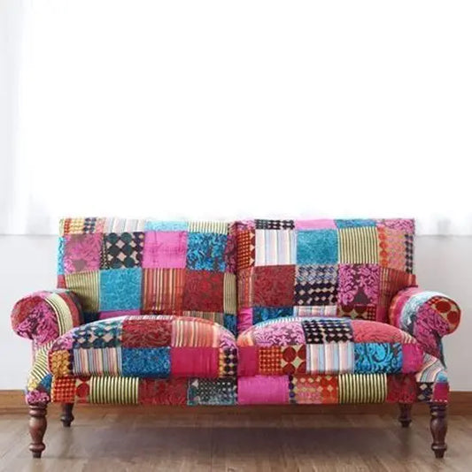 A multicolored patchwork fabric sofa with ornate wooden legs and a traditional yet contemporary design.