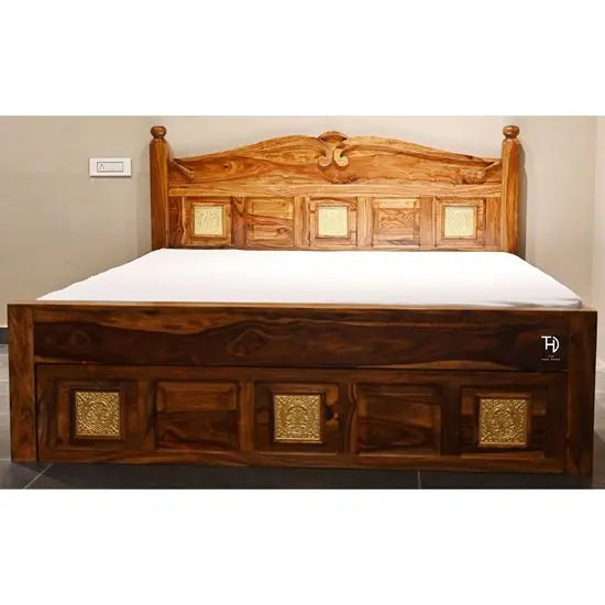 A traditional Nawab king size bed made of Sheesham wood with brasswork, featuring a storage drawer and decorative panels at the headboard.