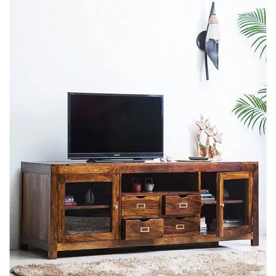 A wooden LokO' TV Cabinet with two door sections and four drawers, placed on a carpeted floor against a wall, with a flat-screen TV on top and decorative items around.