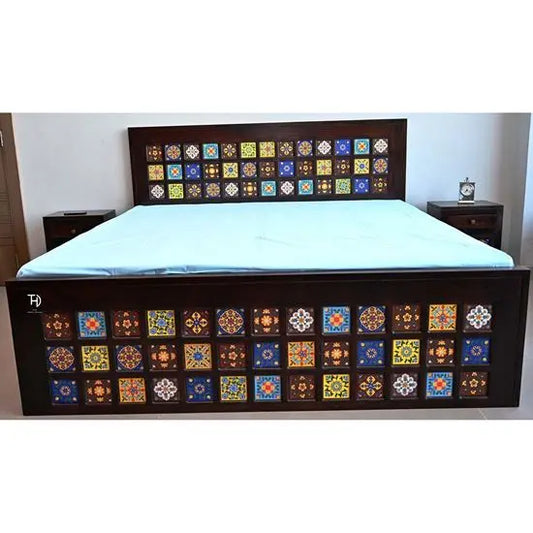 A double bed with a brown wooden frame featuring ceramic tile patterns, placed in a room setting with bedding and a nightstand.