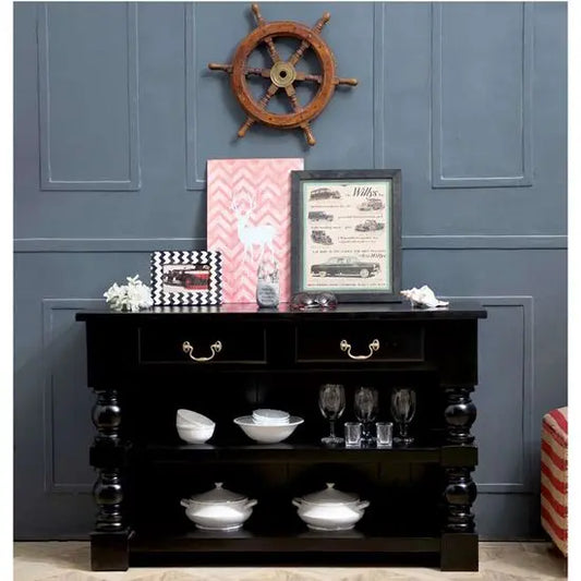 A black console table made of solid wood with lathe legs and brass handles.