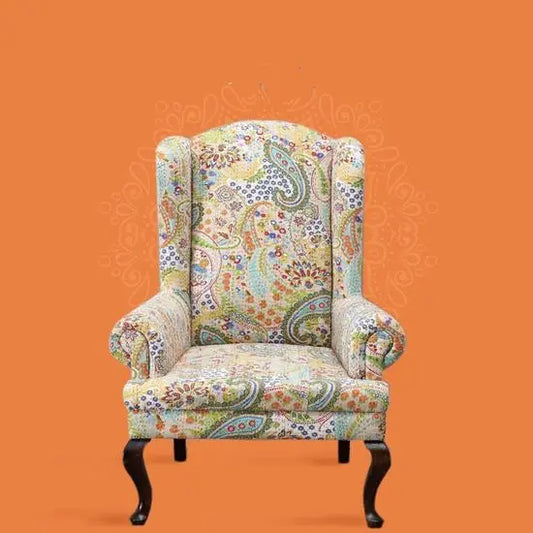 A Katha Maharaja sofa with a floral fabric design on a wing chair-style frame with wooden legs.