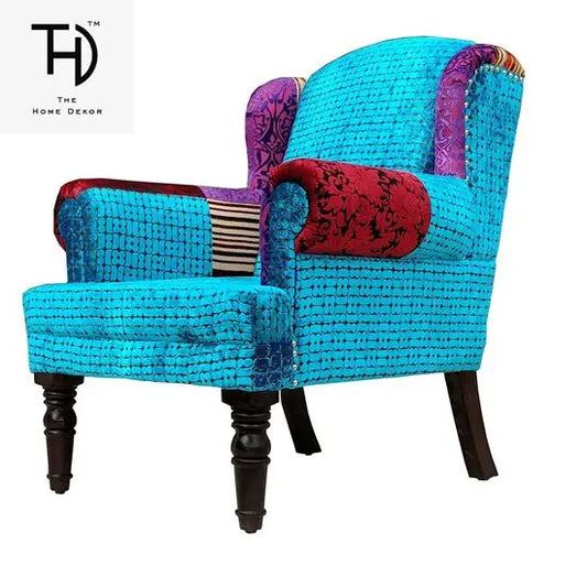 A blue Maharaja sofa with velvet upholstery and wooden legs, featuring a single seat and patchwork on the armrest.