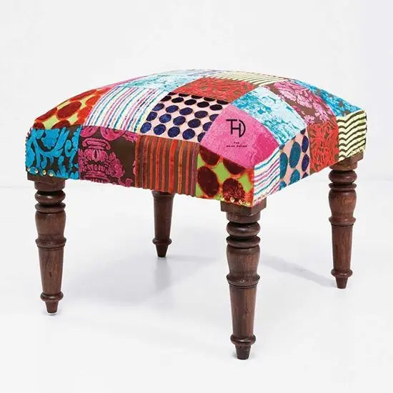 A multicolored patchwork fabric covered stool in square shape.