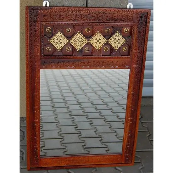 A vintage mirror frame with a brown honey-like finish and decorative elements in a geometric pattern.