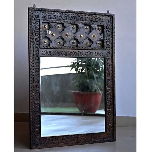 A vintage style mirror frame made of wood with brass work, walnut color, standing on the floor.