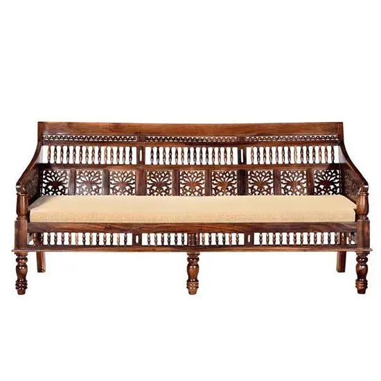 A three-seater vintage sofa with a sturdy Sheesham wood frame, hand-carved details, and a cushioned seat in a warm honey color.