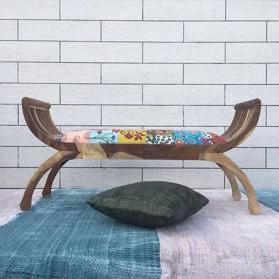 A wooden bench with a multicolored upholstered padded seat.
