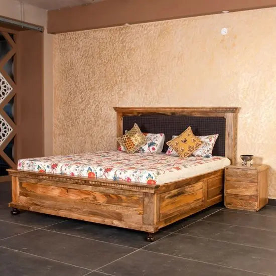 A king-size double bed with a wooden frame and brown upholstered headboard.