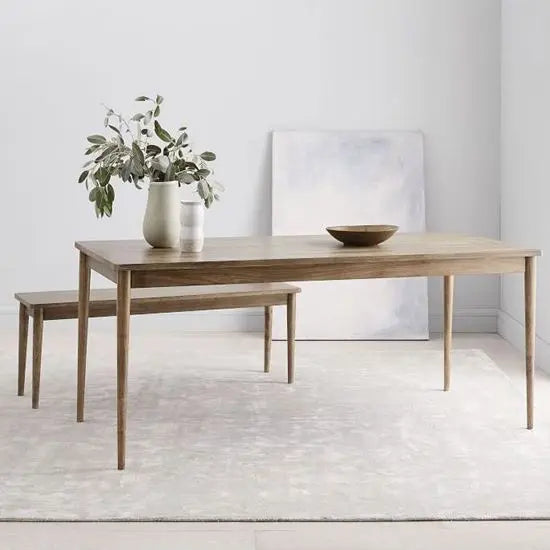 A simple wooden dining table with turned-round legs, accompanied by a matching bench. suggesting a homey dining setting.
