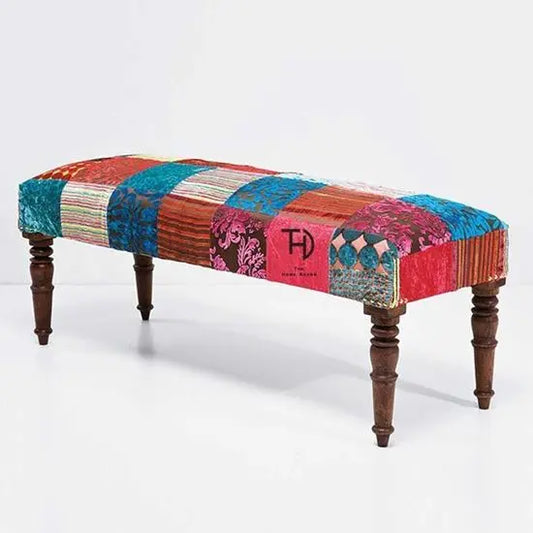 A 2 seater bench with multicolor patchwork fabric upholstery and wooden legs.