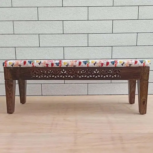 A wooden bench with off white color cushion covered in soft fabric with a floral pattern.