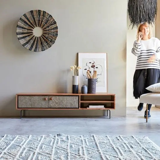 A Jarrah TV cabinet with two doors and two open shelves, featuring metal knobs and wooden legs, placed in a room with decorative items on top.
