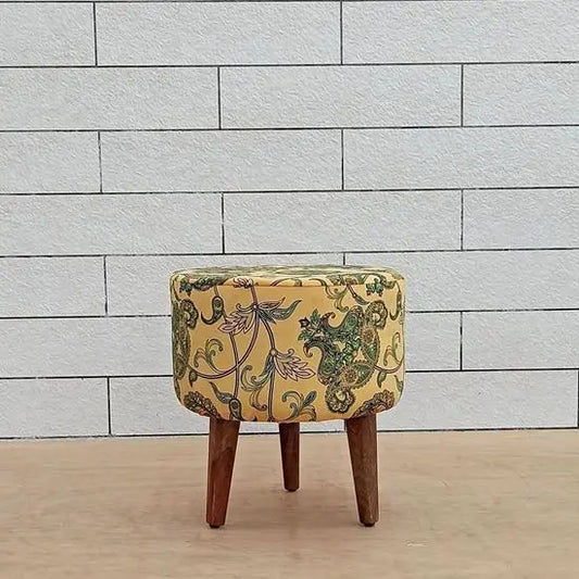 A yellow upholstered pouf with a floral pattern, on three wooden legs.