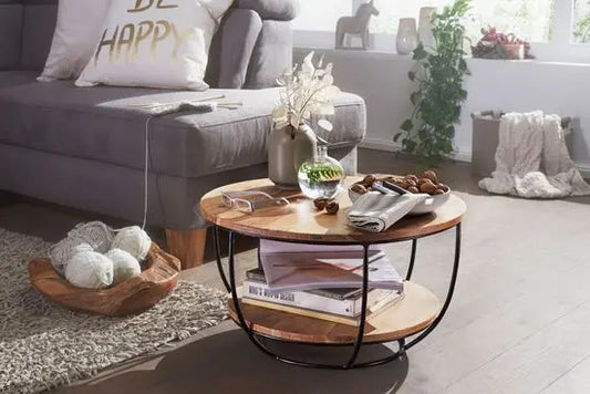 A round coffee table with acacia wood top and black metal frame with two shelves for keeps items.