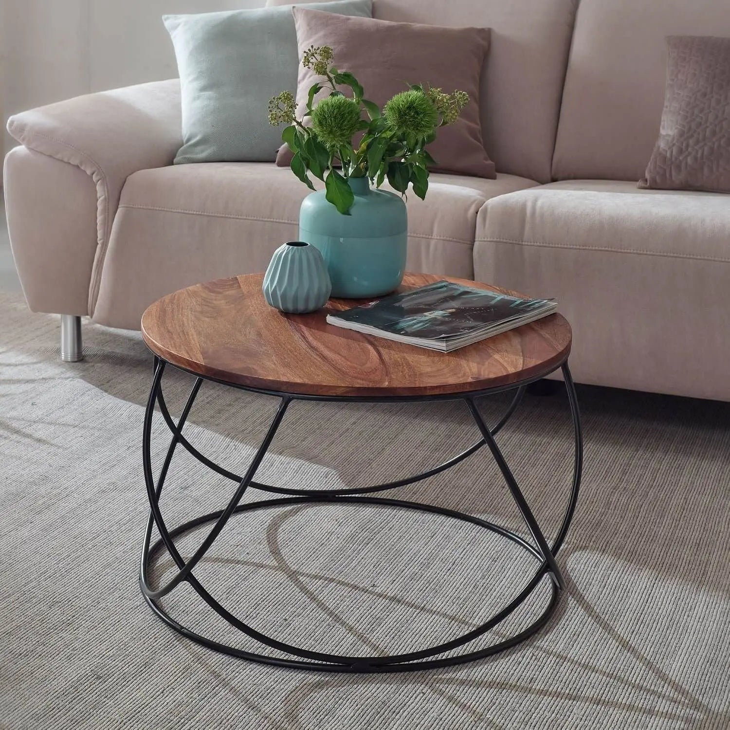 A round coffee table with a wooden top and black metal base.