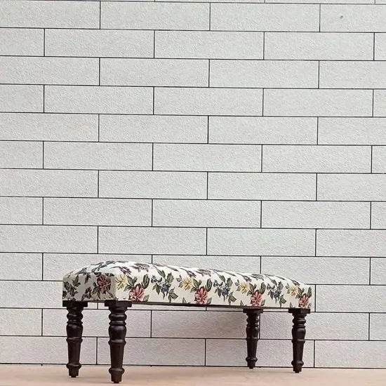 A floral fabric-upholstered bench with dark wood legs.