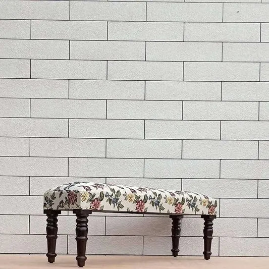 A floral fabric-upholstered bench with dark wood legs.