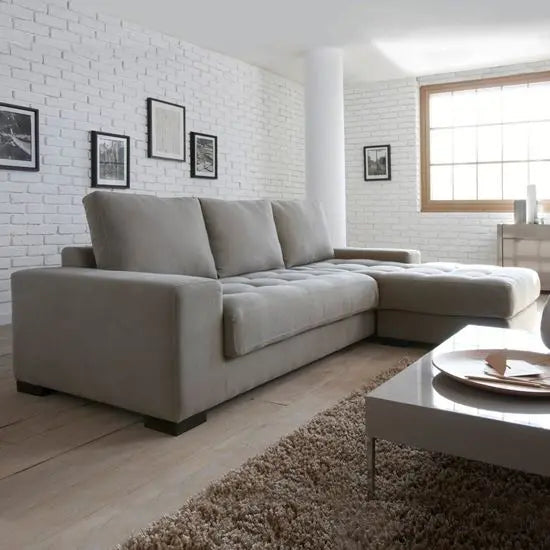 An L-shaped sofa in a living room setting with a modern design, light gray fabric, and wooden sofa Structure.
