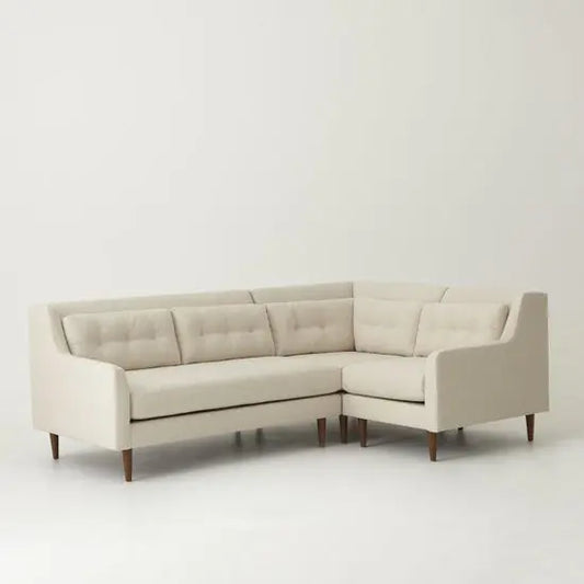 Straight line Close-up of a beige L-shaped sofa with a cushioned backrest and button details. Best corner sofa online.
