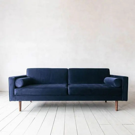 A blue velvet three-seater sofa with Sheesham wood legs.