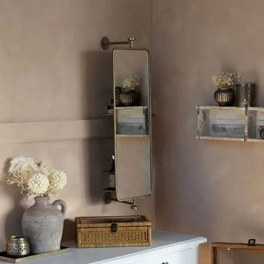 A rustic golden finish metal mirror mounted on a wall, with storage compartments and a revolving design.