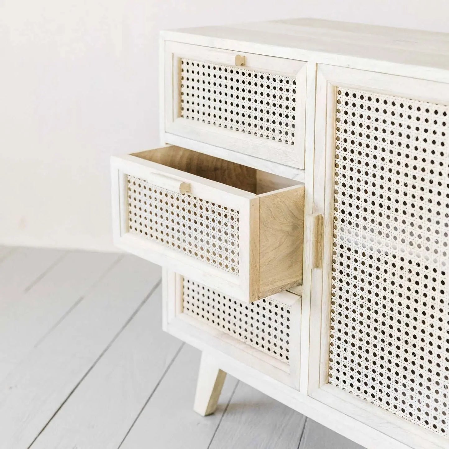 White solid wood cabinet with rattan door and drawers.