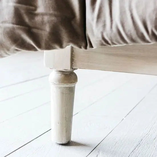 The image shows a traditional style bed with a upholstered back and wooden legs, set in a bedroom environment.