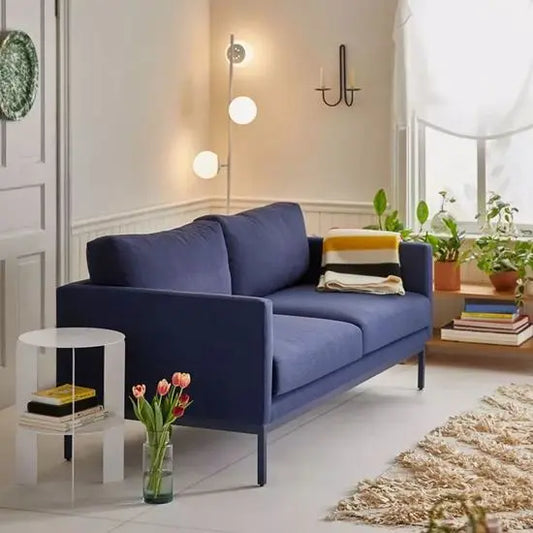 A blue Helios sofa with a metal base is arranged in a living room.