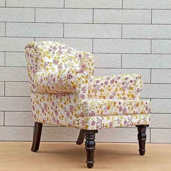 A Genova Wing Chair with golden velvet upholstery featuring a floral pattern.