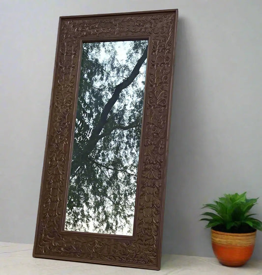 A rustic Aklavya mirror frame made of Sheesham wood with intricate hand-carved details.