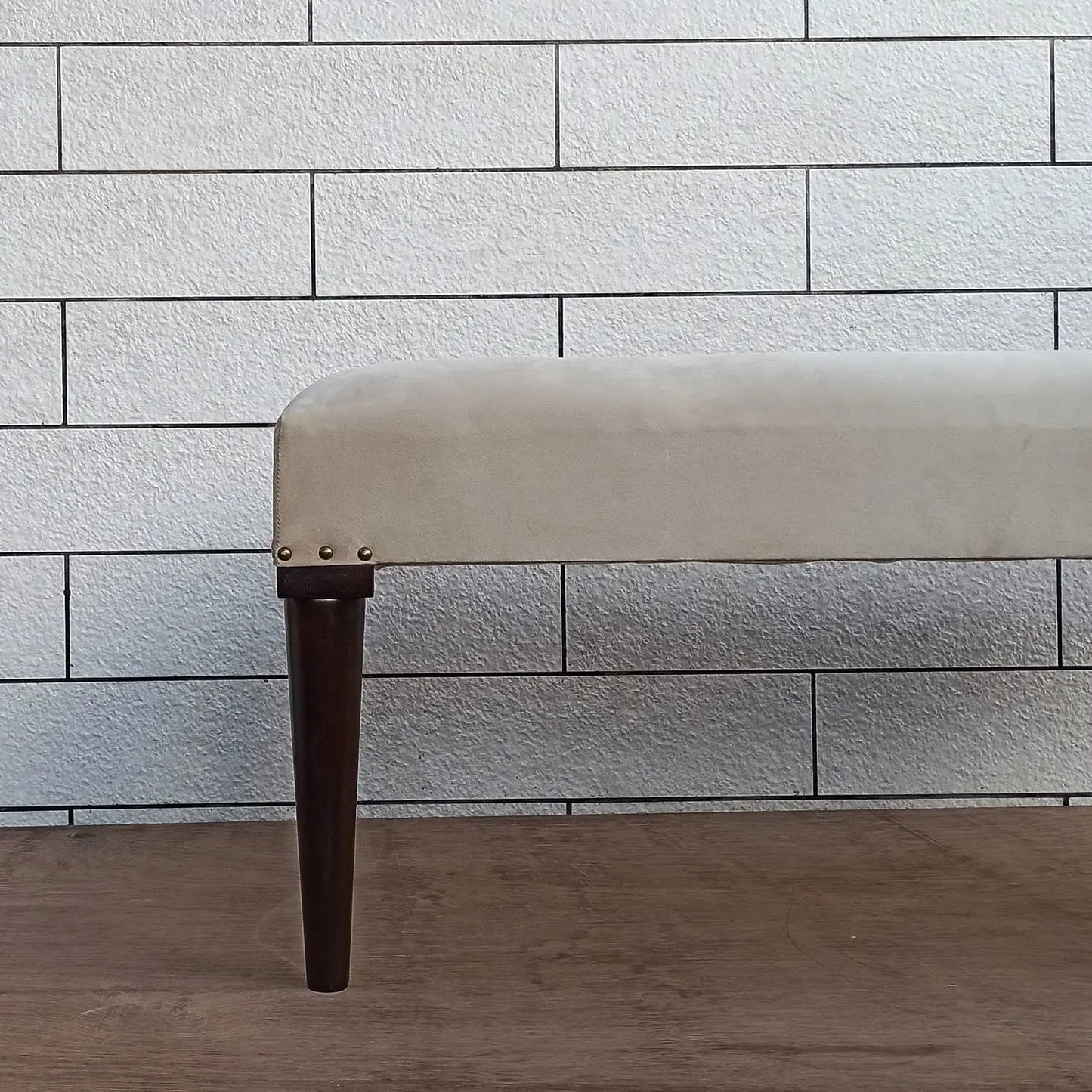 Beige carvin bench with dark round wooden legs.