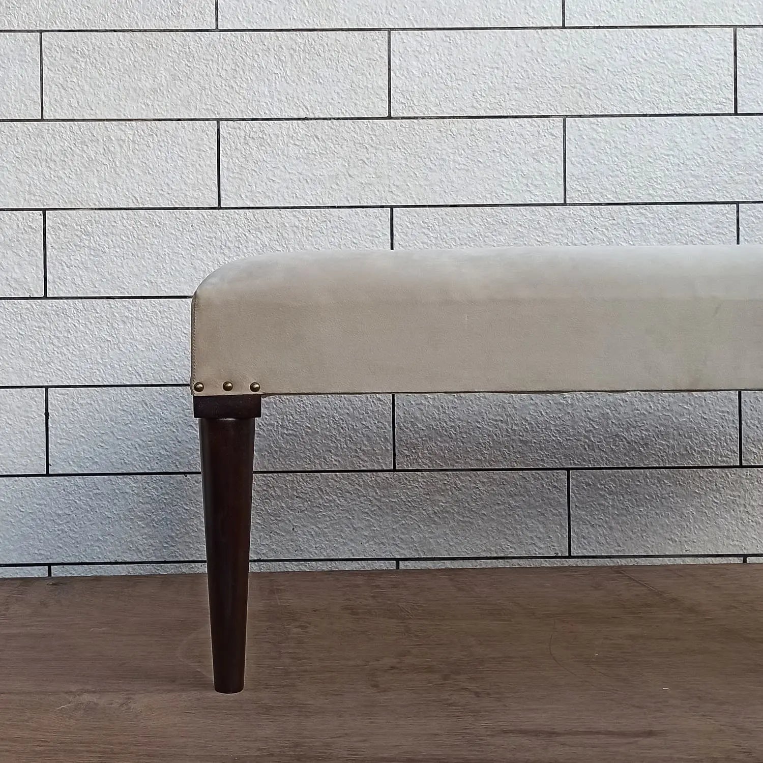Beige carvin bench with dark round wooden legs.