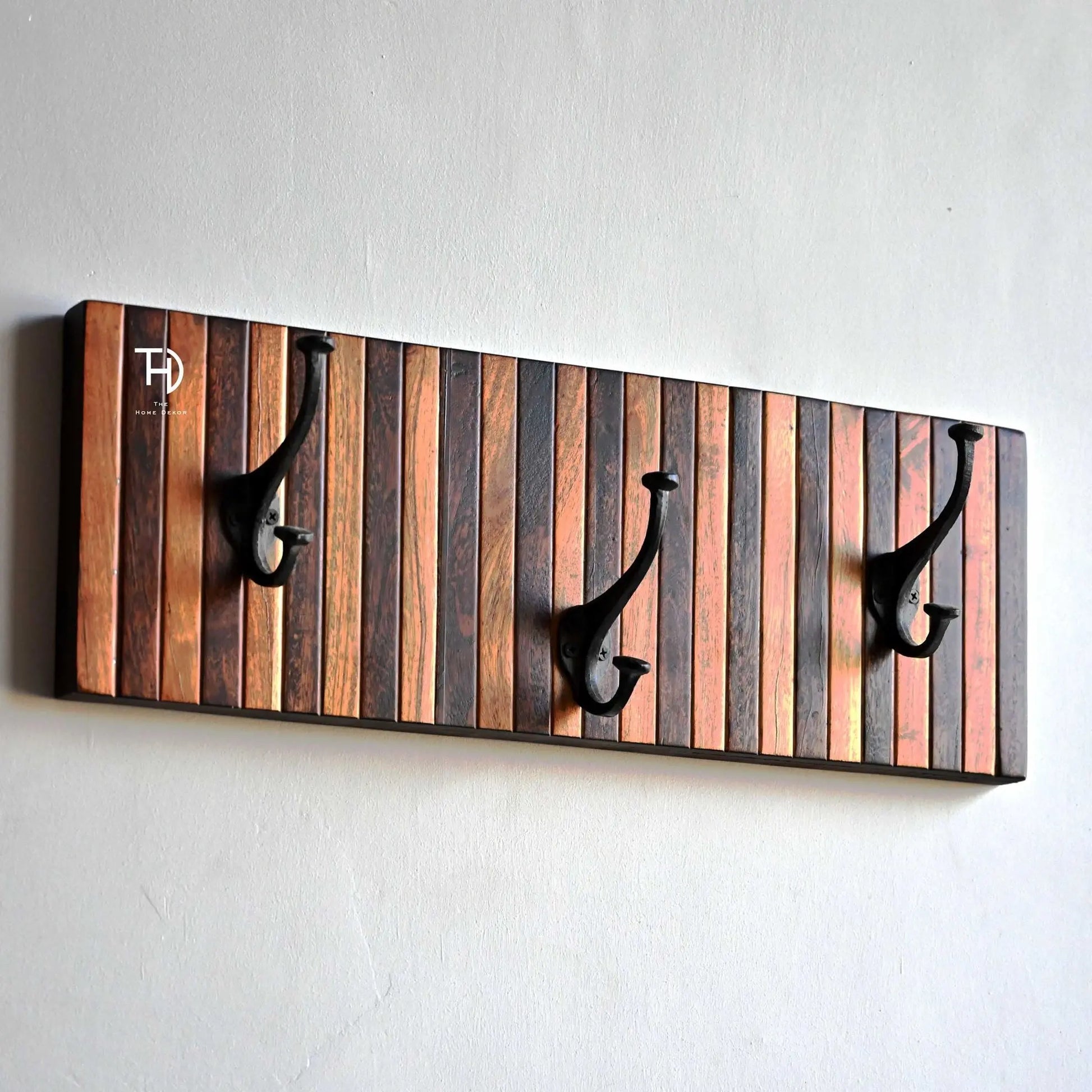 Wooden wall hook with striped design and three black hooks.