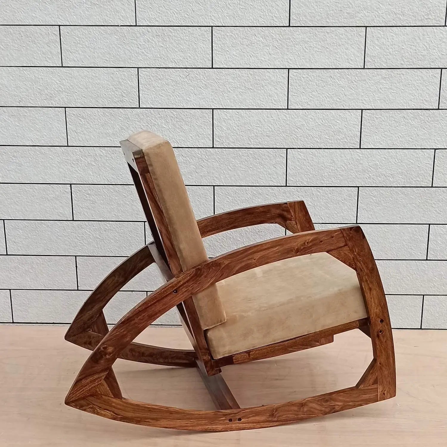 Solid wood designer rocking chair with beige cushion.