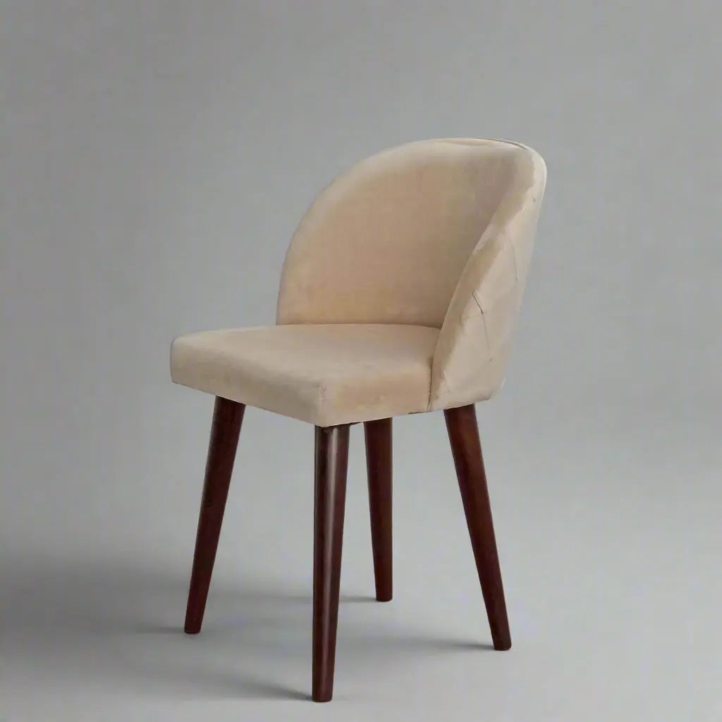 A beige upholstered chair with an upholstered backrest and seat, featuring knockdown sheesham wood legs, in a restaurant or dining room.