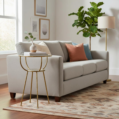 A Hammering Side Table with a hammered finish golden color metal base and a clear glass top.